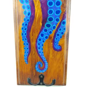 Colgachaves de madeira cun deseño pintado de tentáculos azuis sobre fondo púrpura e gancho metálico negro de dúas pranchas na parte dereita.