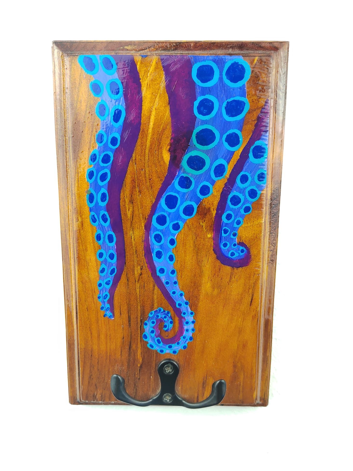 Colgachaves de madeira cun deseño pintado de tentáculos azuis sobre fondo púrpura e gancho metálico negro de dúas pranchas na parte dereita.