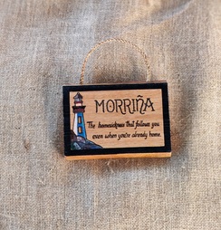 Cartel Morriña pirogravado en madeira de castiñeiro, con ilustración pintada a man dun faro en tons azuis e vermellos, colgado con corda de cánamo
