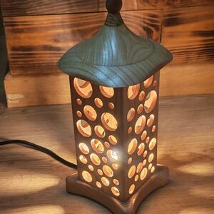 Lámpada artesanal Pagoda encesa, farol de madeira de castiñeiro con calados circulares e pináculo de Makoré, colección Vagalumes