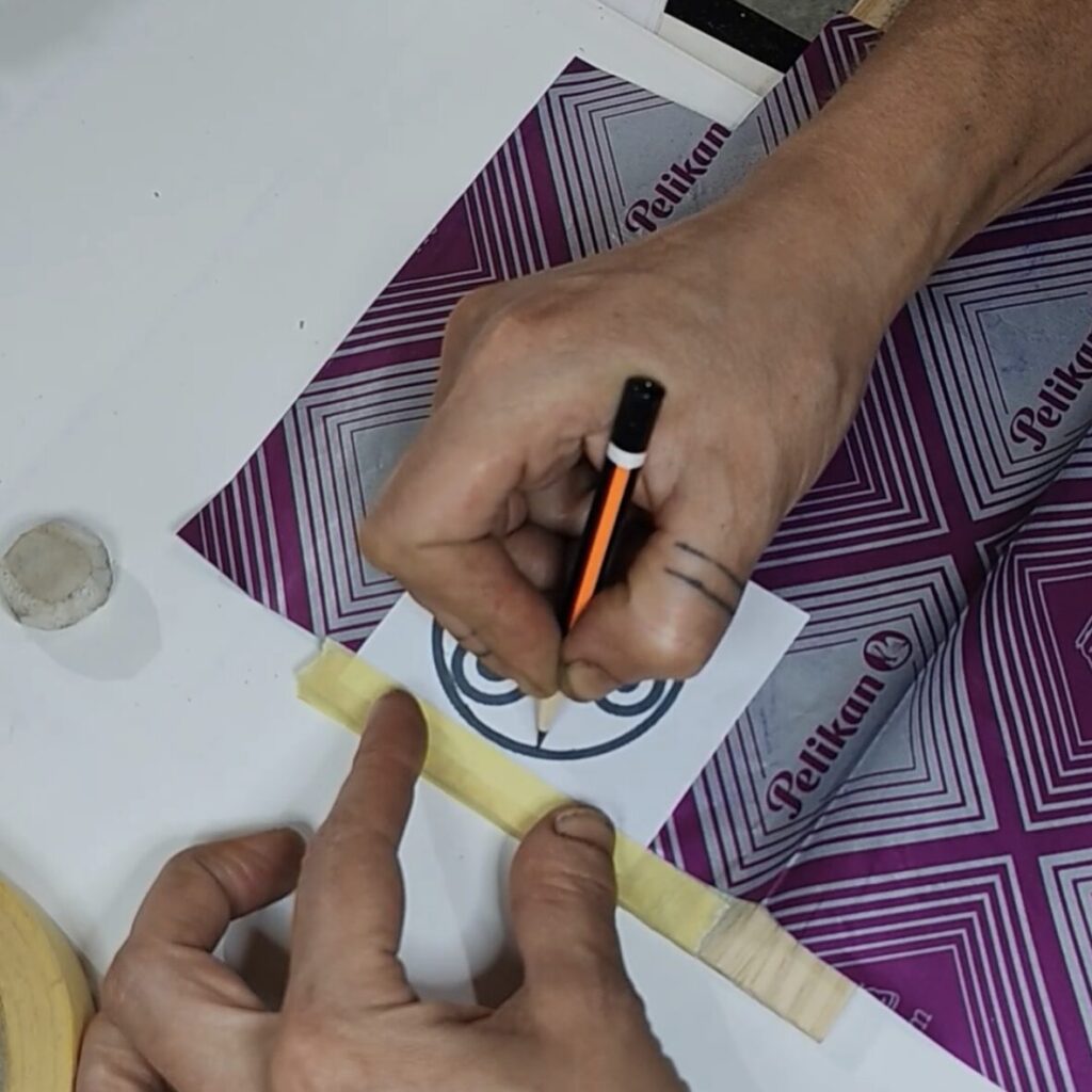 Cinta pegada suxeitando o deseño sobre a madeira