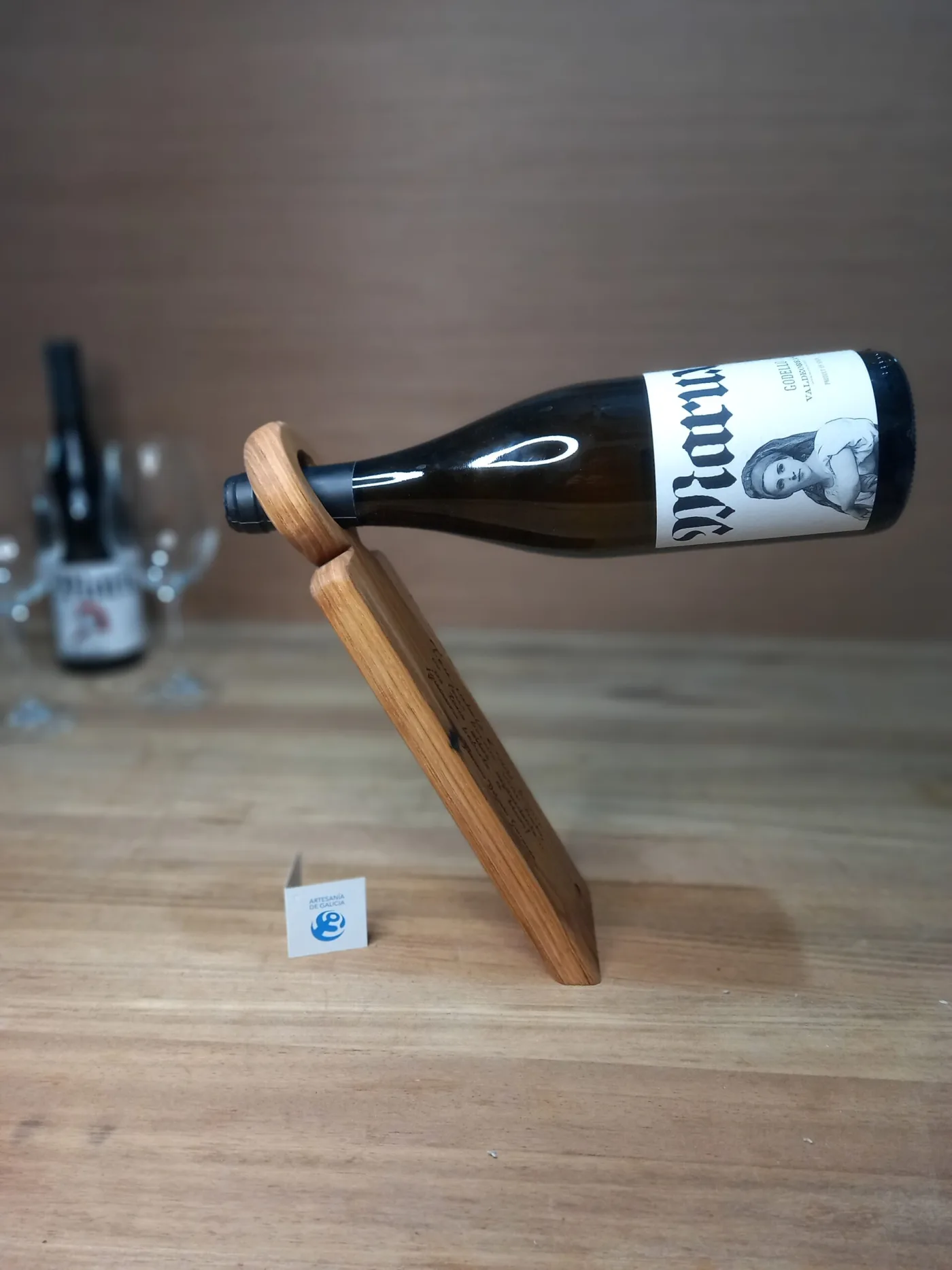 Botelleiro de madeira que sostén unha botella de viño en equilibrio, sobre unha mesa