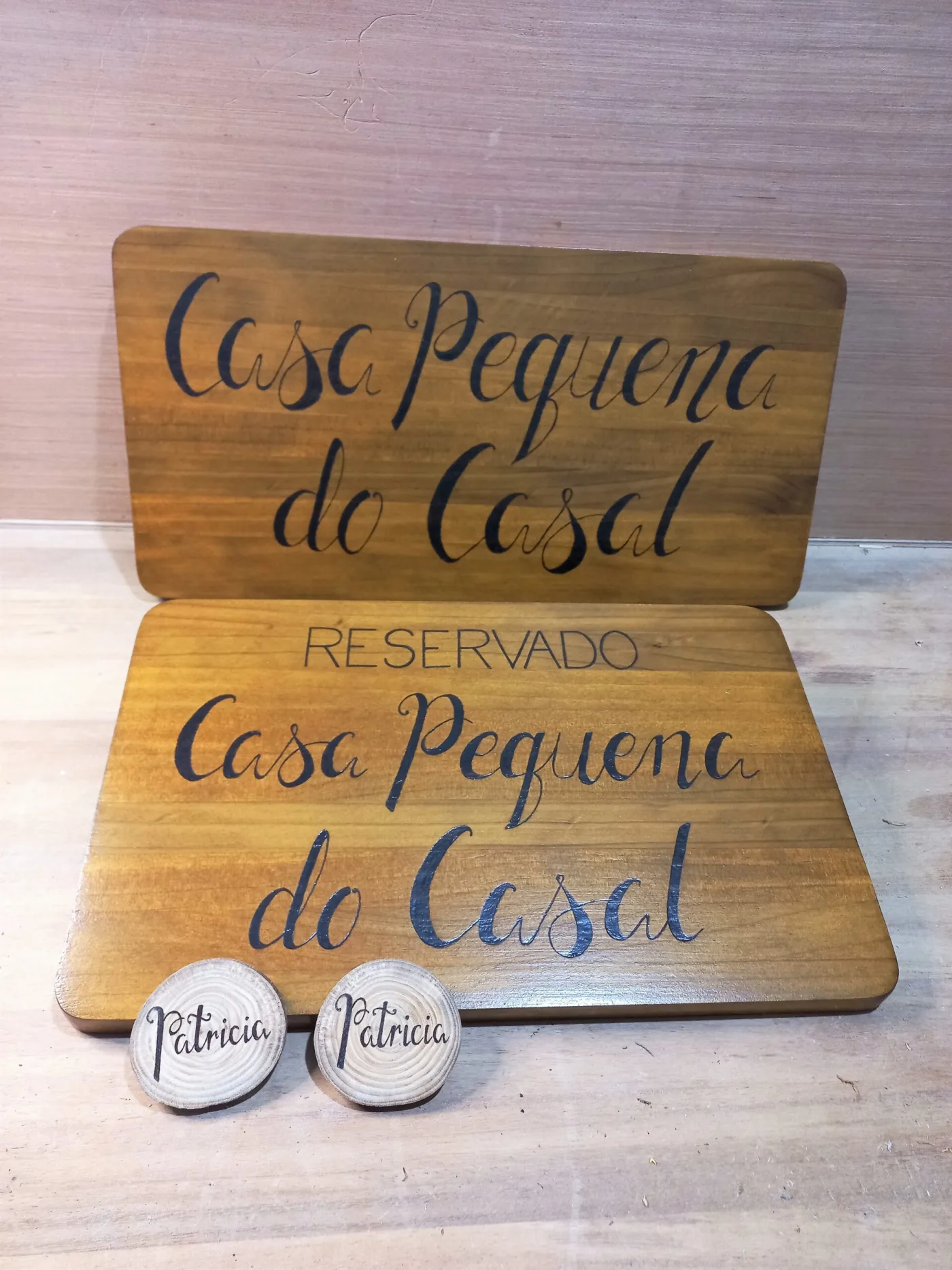 Carteis de madeira pirogravados Casa Pequena do Casal e Reservado para unha casa rural, con dúas pedras co nome