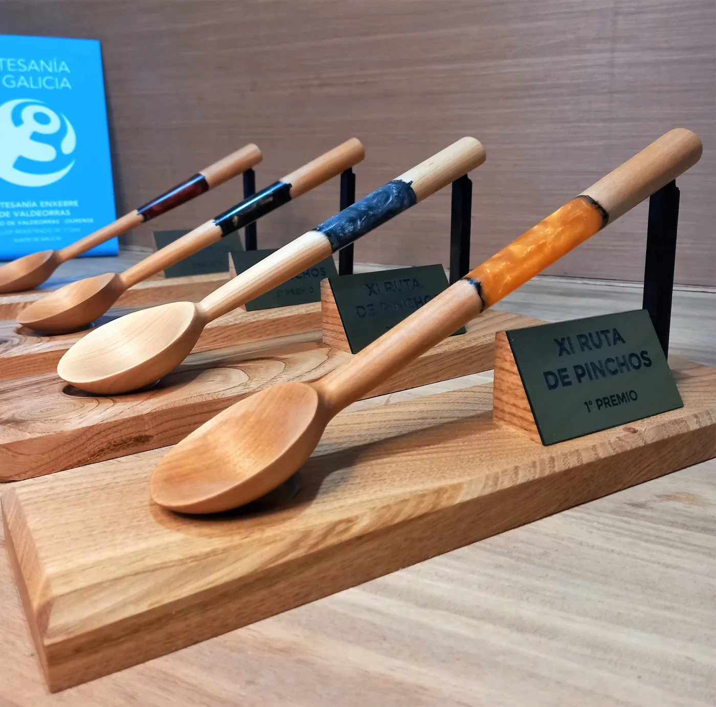 Culleres de madeira con detalles de resina como premio da Ruta de Pinchos, sobre unha base de madeira